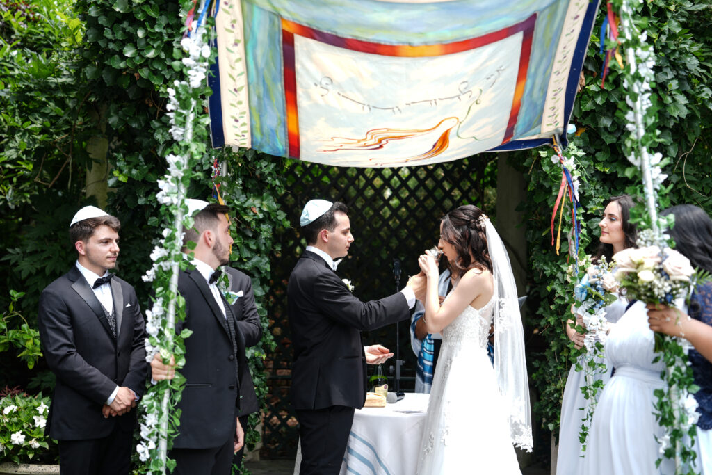 Bride and groom under chuppah during Westbury Manor garden wedding